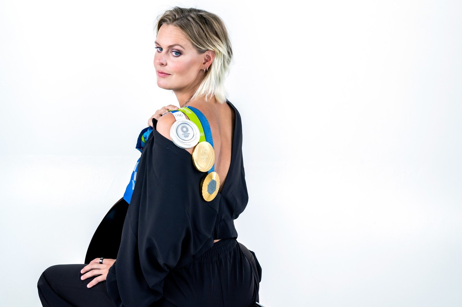 Sharon van Rouwendaal wearing a black outfit with her Olympic medals over her shoulder