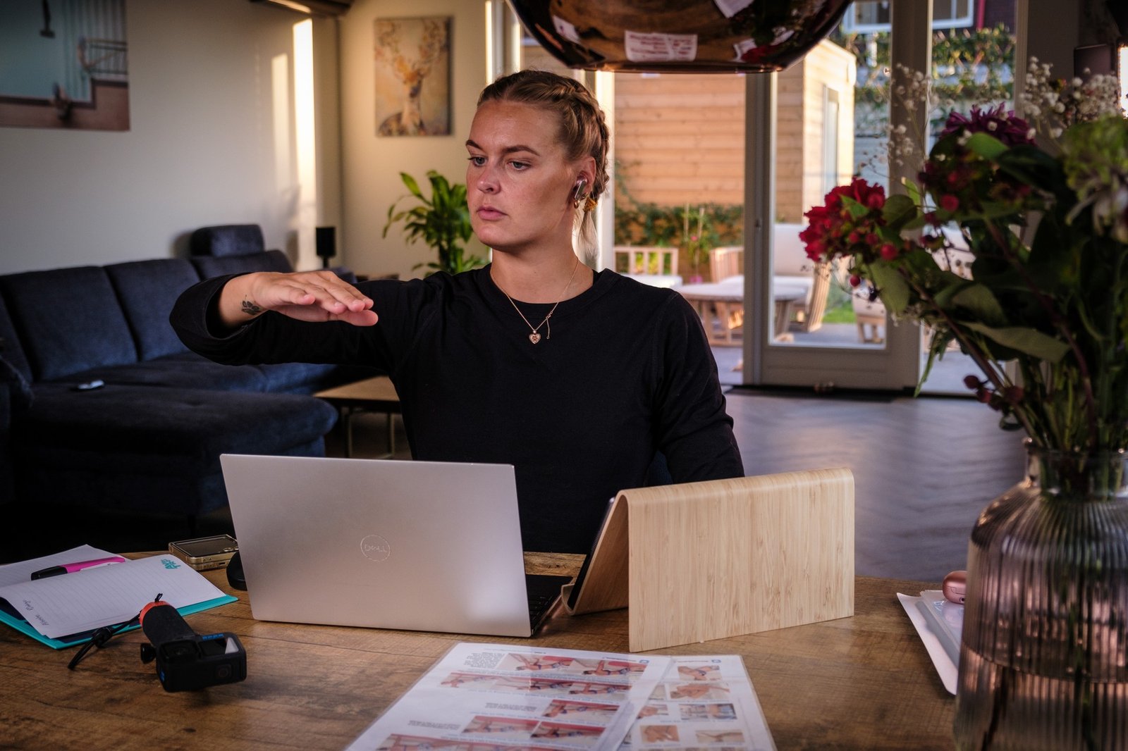 Sharon demonstrating a swimming hand position beside her laptop during an online conversation.